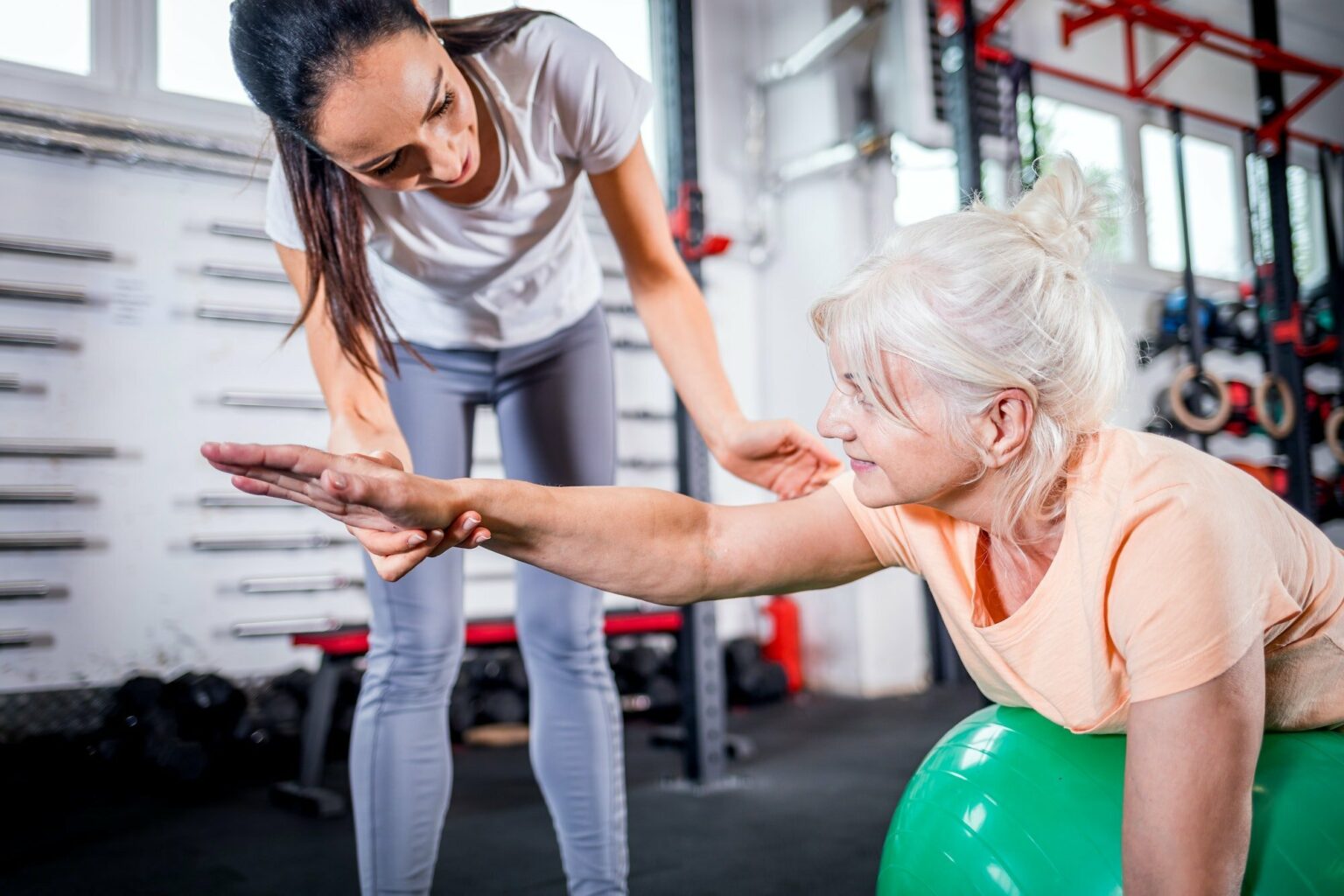 Senior woman with trainer doing rehab using pilates ball in the rehabilitation center
