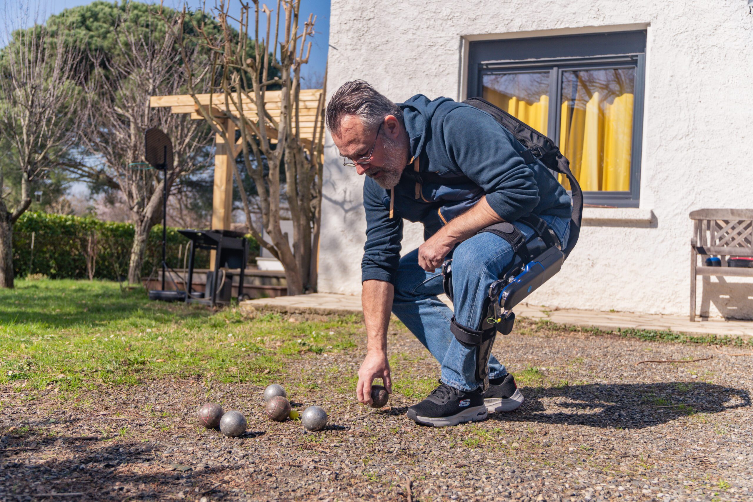 Man wearing DREEVEN robotic knee brace pends down to pick up an object on an outdoor hiking trail.